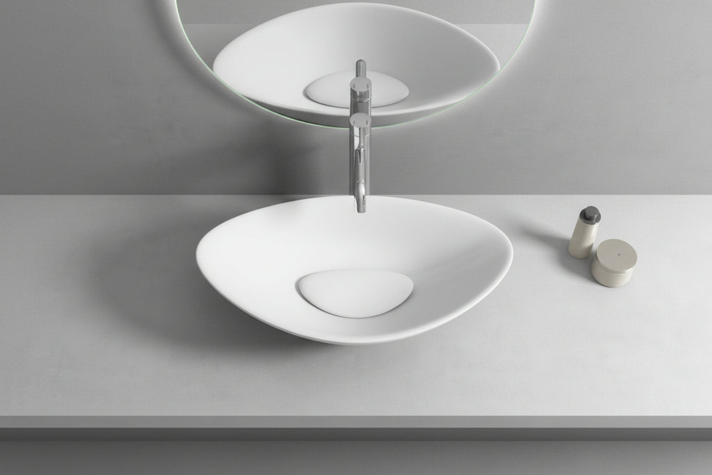 White oval sink on a gray countertop with a mirror above