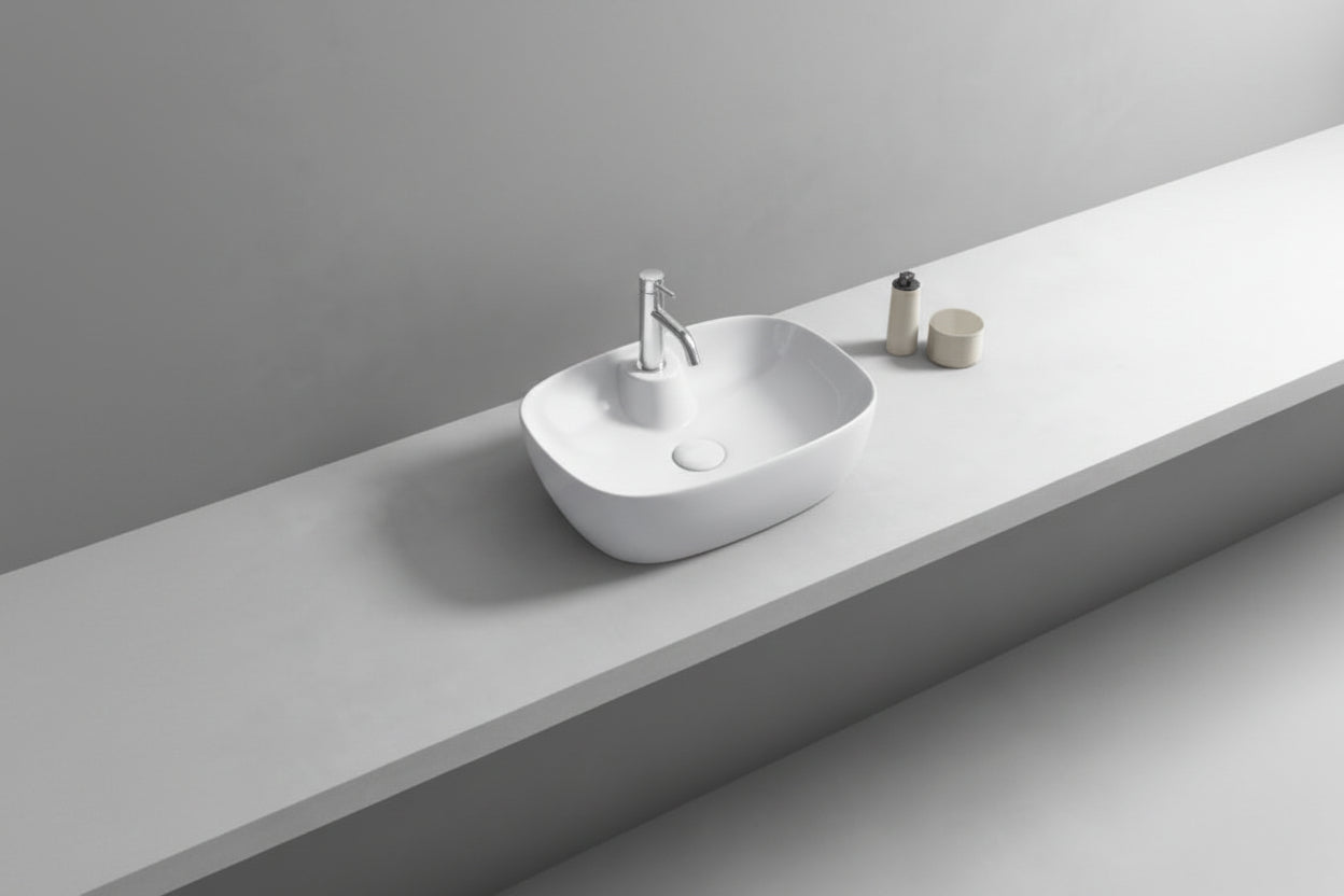 Bathroom vanity with a white sink and round mirror on a light gray wall.