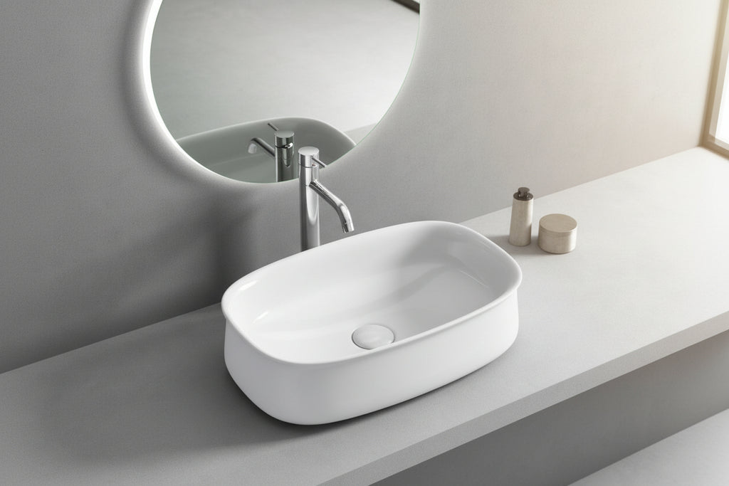 White oval sink on a gray countertop with a mirror above