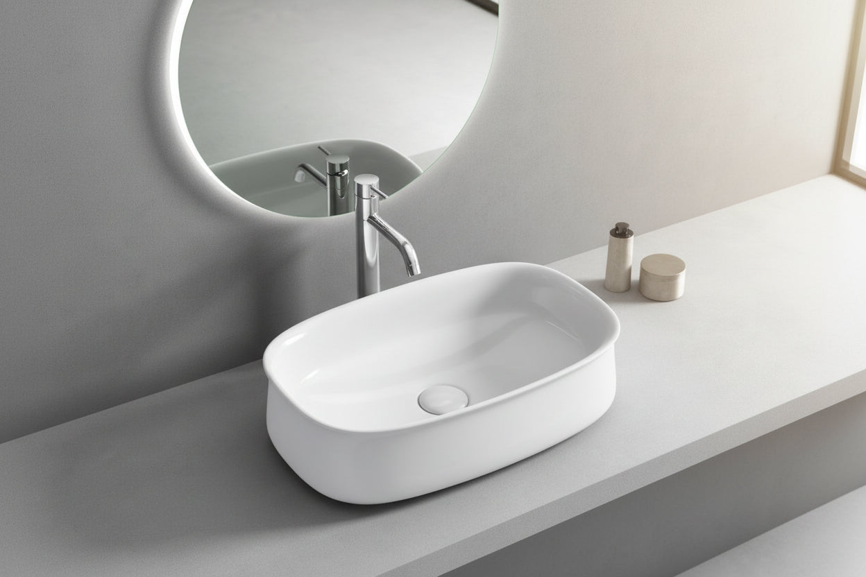 White oval sink on a gray countertop with a mirror above